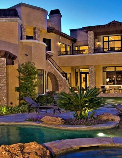 A mediterranean style home with a pool and landscaping.