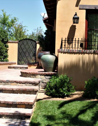 A tan house with steps leading to a patio.